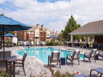A pool surrounded by chairs and umbrellas.